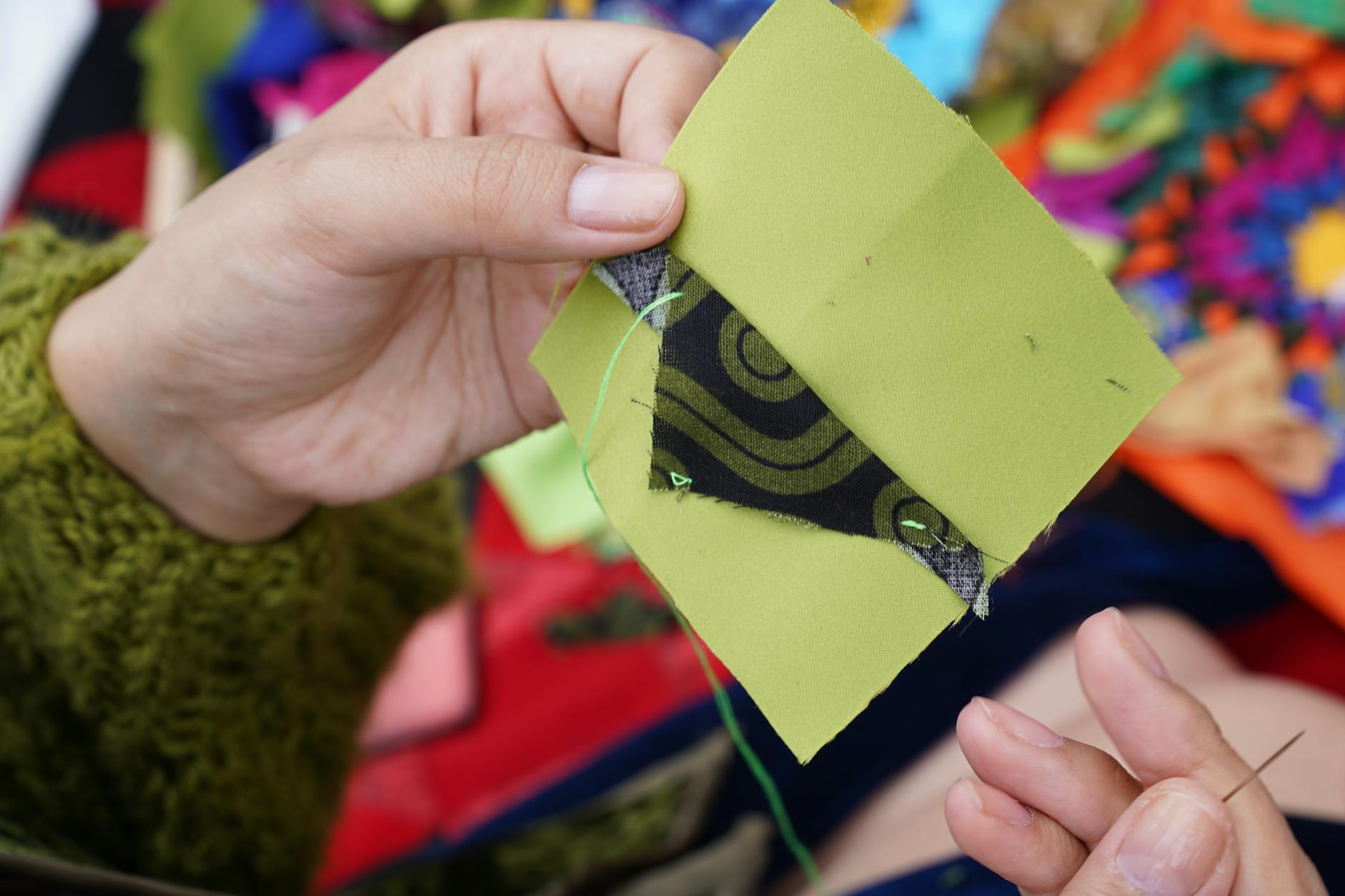 Dłonie szyjące kolorowy patchwork tradycyjną techniką quiltingu