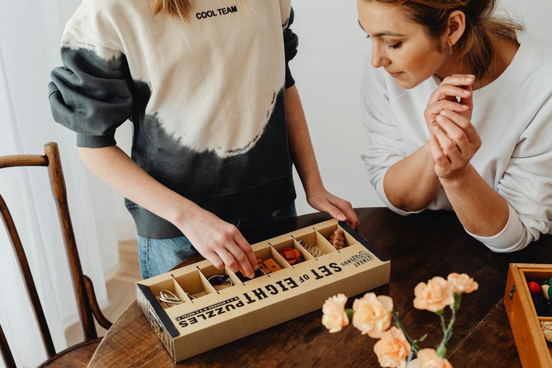 Dwie kobiety rozwiązują układankę z pudełkiem z zagadkami w domu