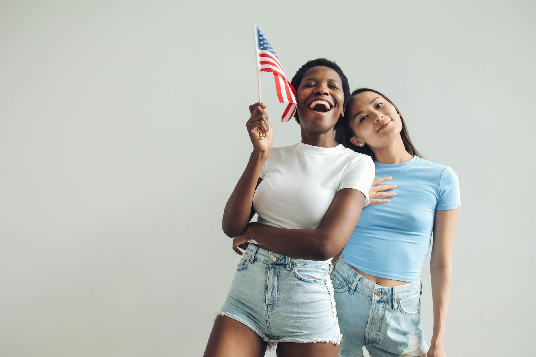 Dwie kobiety w domu radośnie trzymają dużą flagę USA