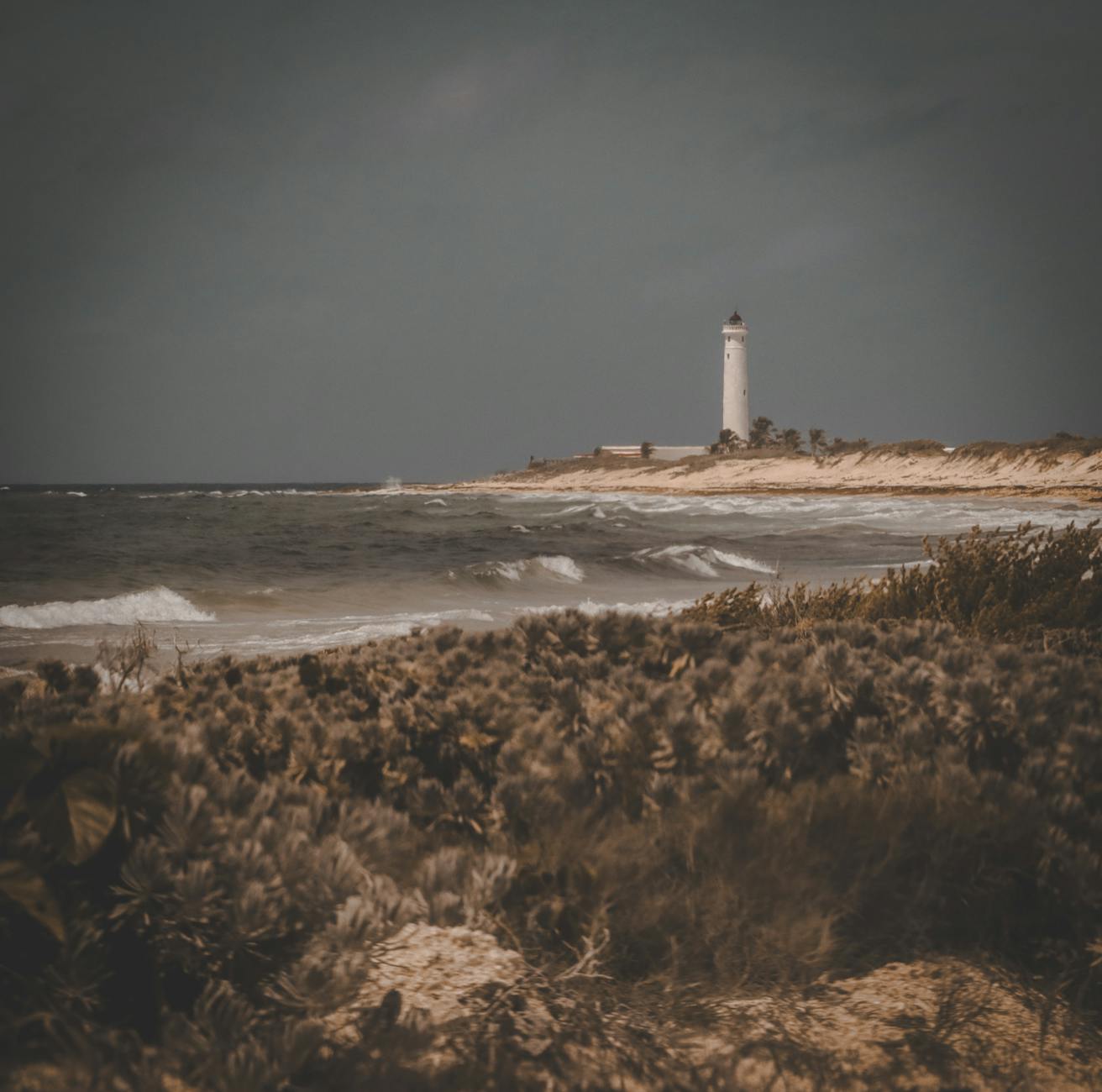 Latarnia morska na klifie nad morzem przy pochmurnym niebie