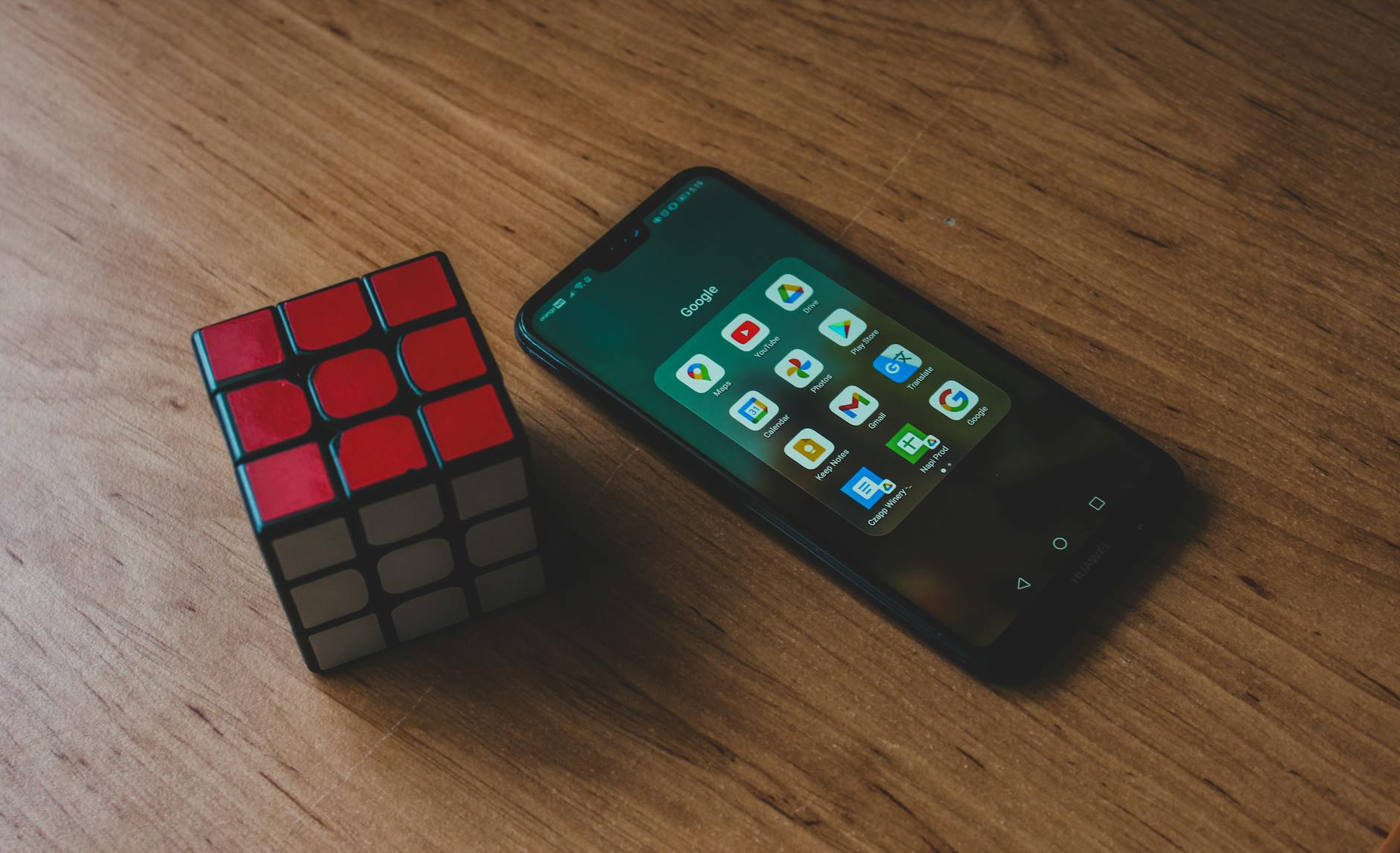 Smartfon z aplikacjami i kostka Rubika na drewnianym stole