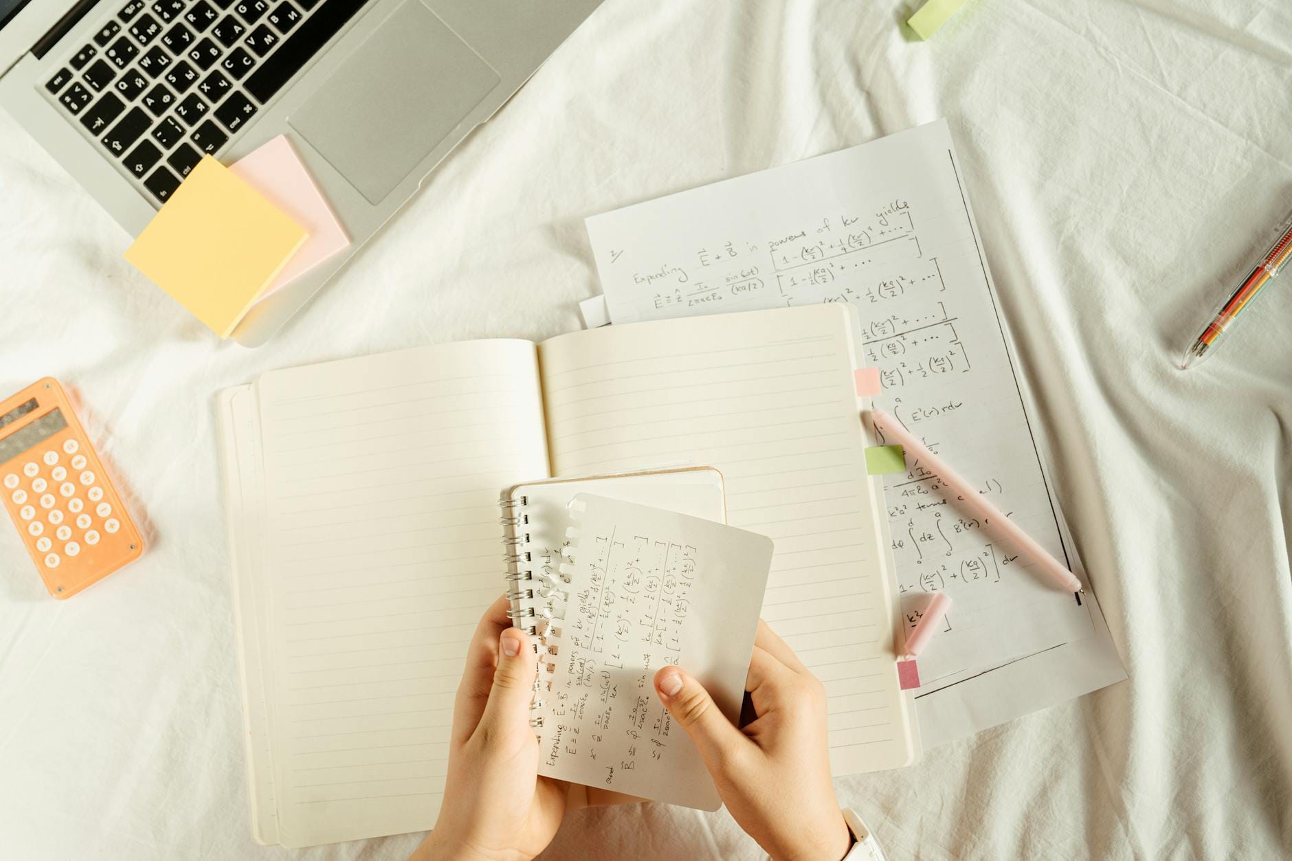 Uczeń trzyma zeszyt z wzorami matematycznymi przy kalkulatorze i laptopie Uczeń trzyma zeszyt z wzorami matematycznymi przy kalkulatorze i laptopie