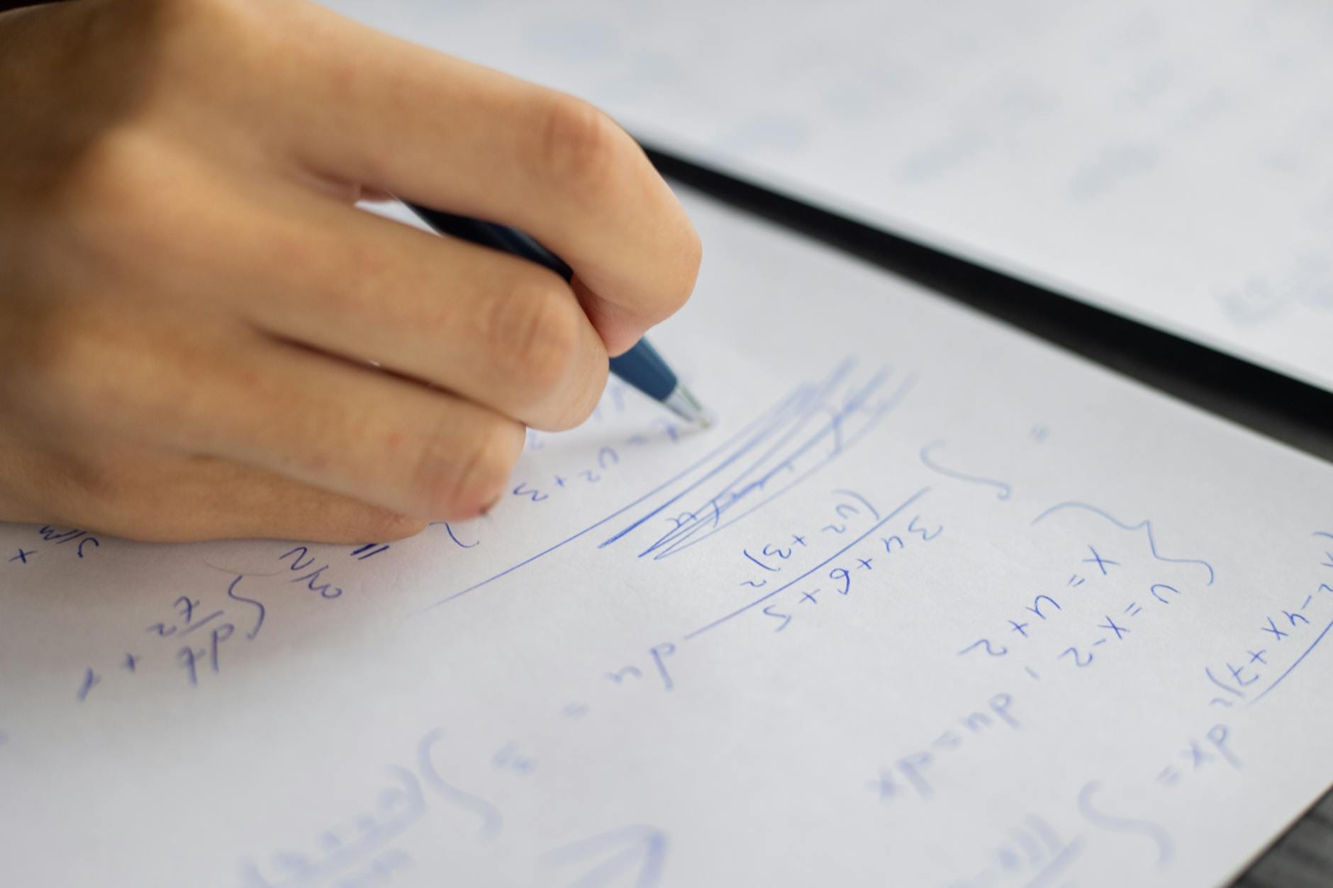 Uczeń zapisuje układ równań na kartce podczas lekcji matematyki