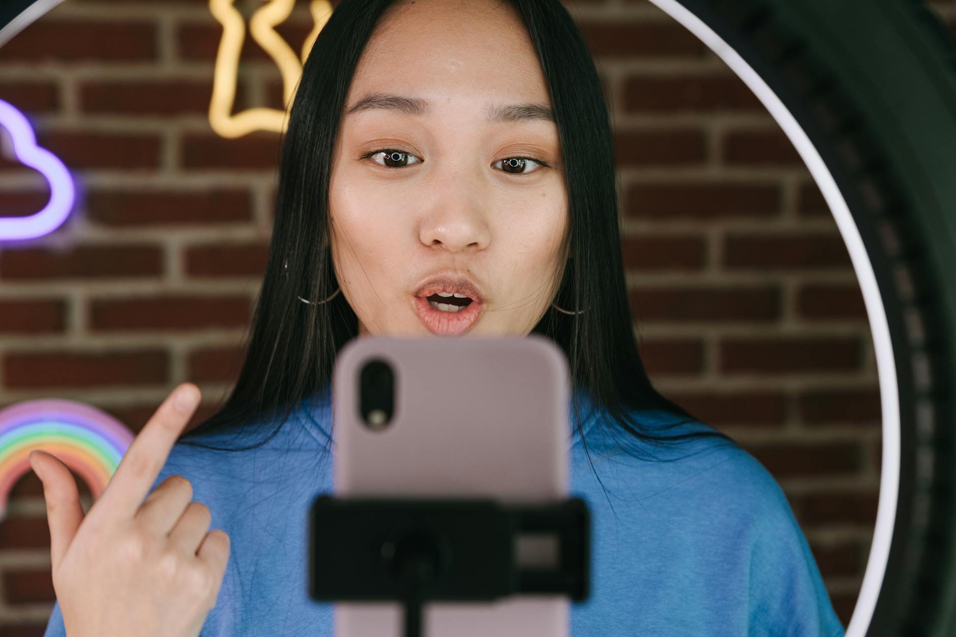 Azjatka nagrywająca osobisty vlog smartfonem przy lampie pierścieniowej