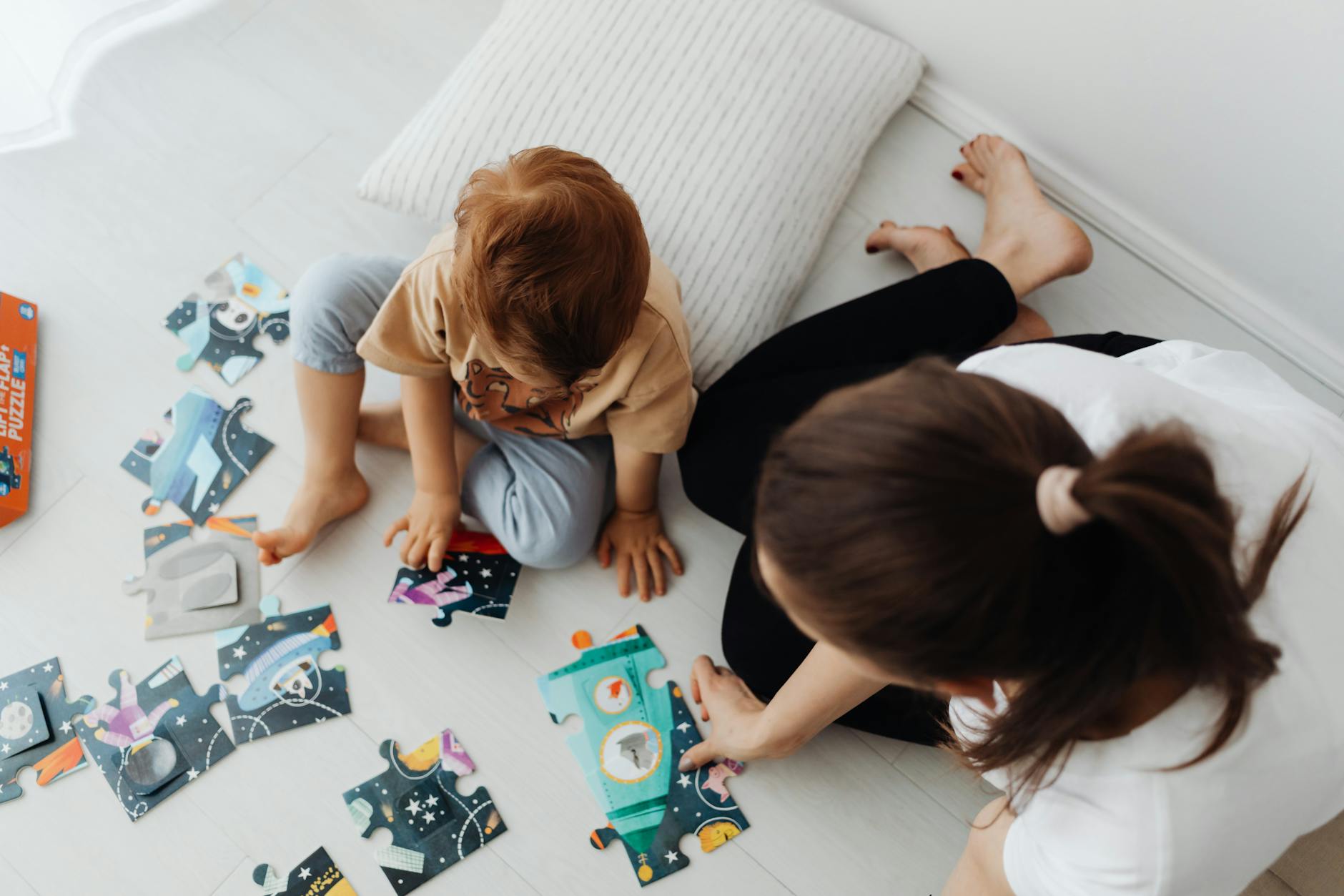 Mama i dziecko układają kosmiczne puzzle na podłodze