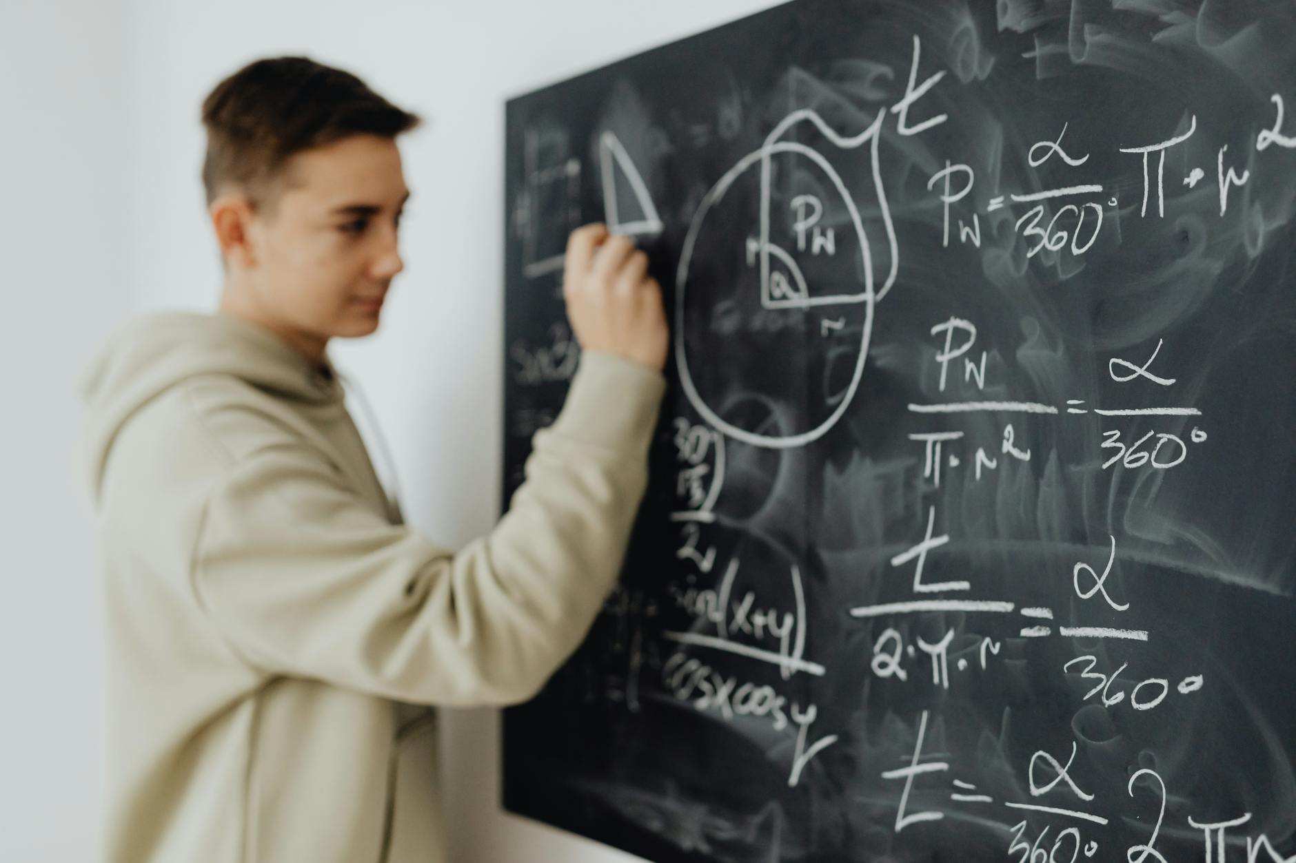 Nastolatek w klasie skupiony nad równaniem matematycznym na tablicy