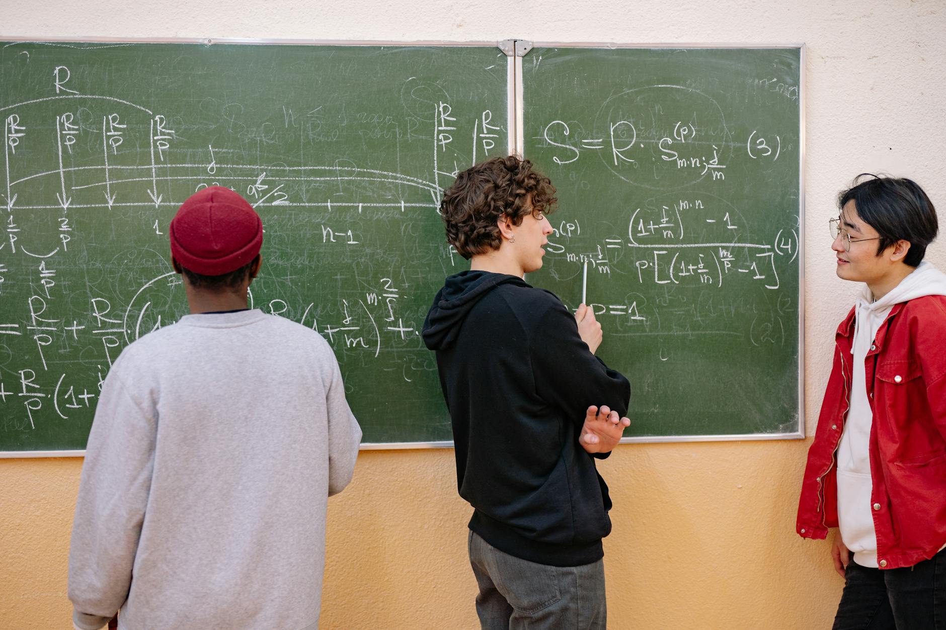 Studenci przy tablicy omawiają równania z prawdopodobieństwa i statystyki