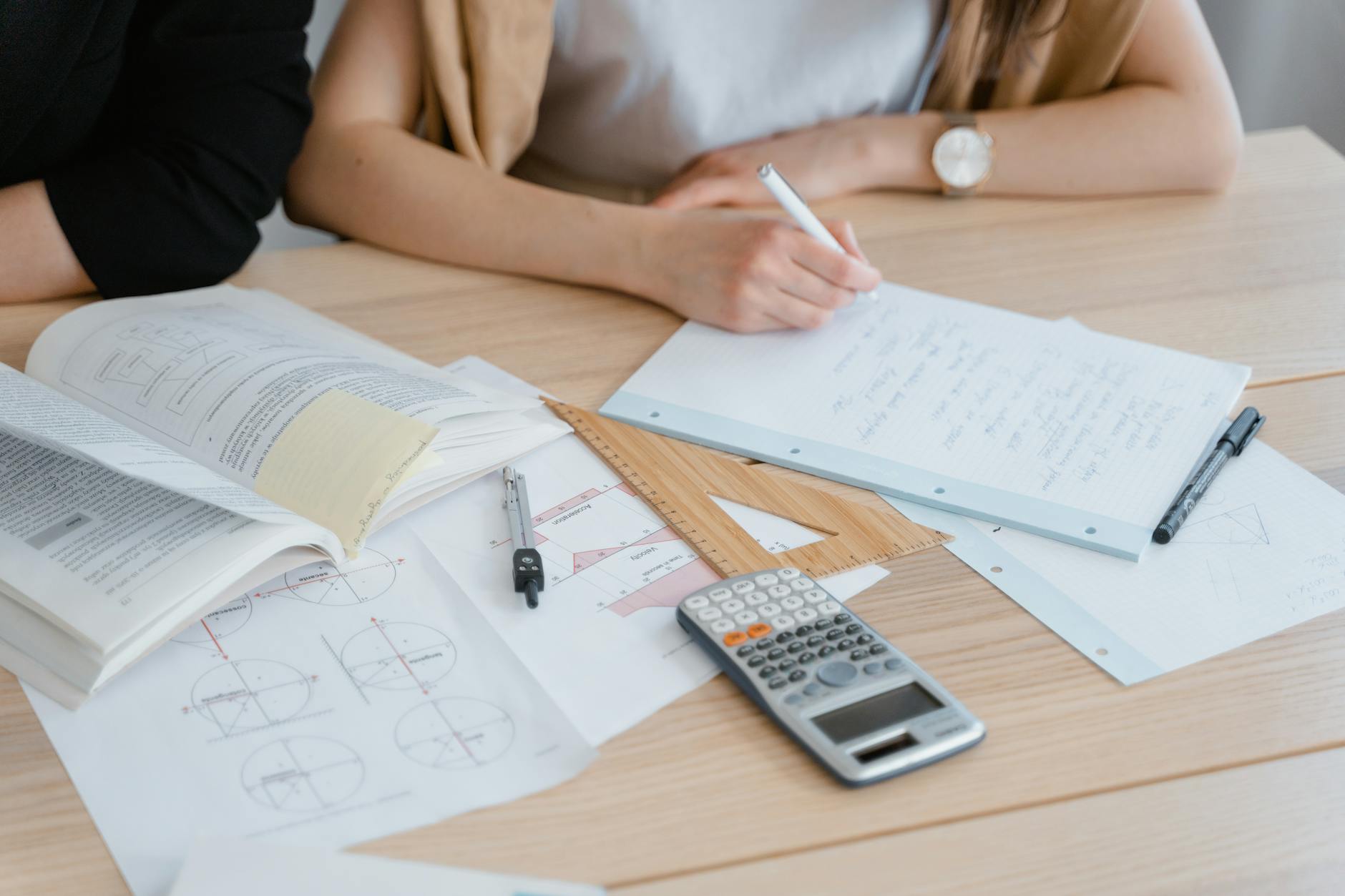 Uczeń robi notatki z matematyki przy książkach i kalkulatorze