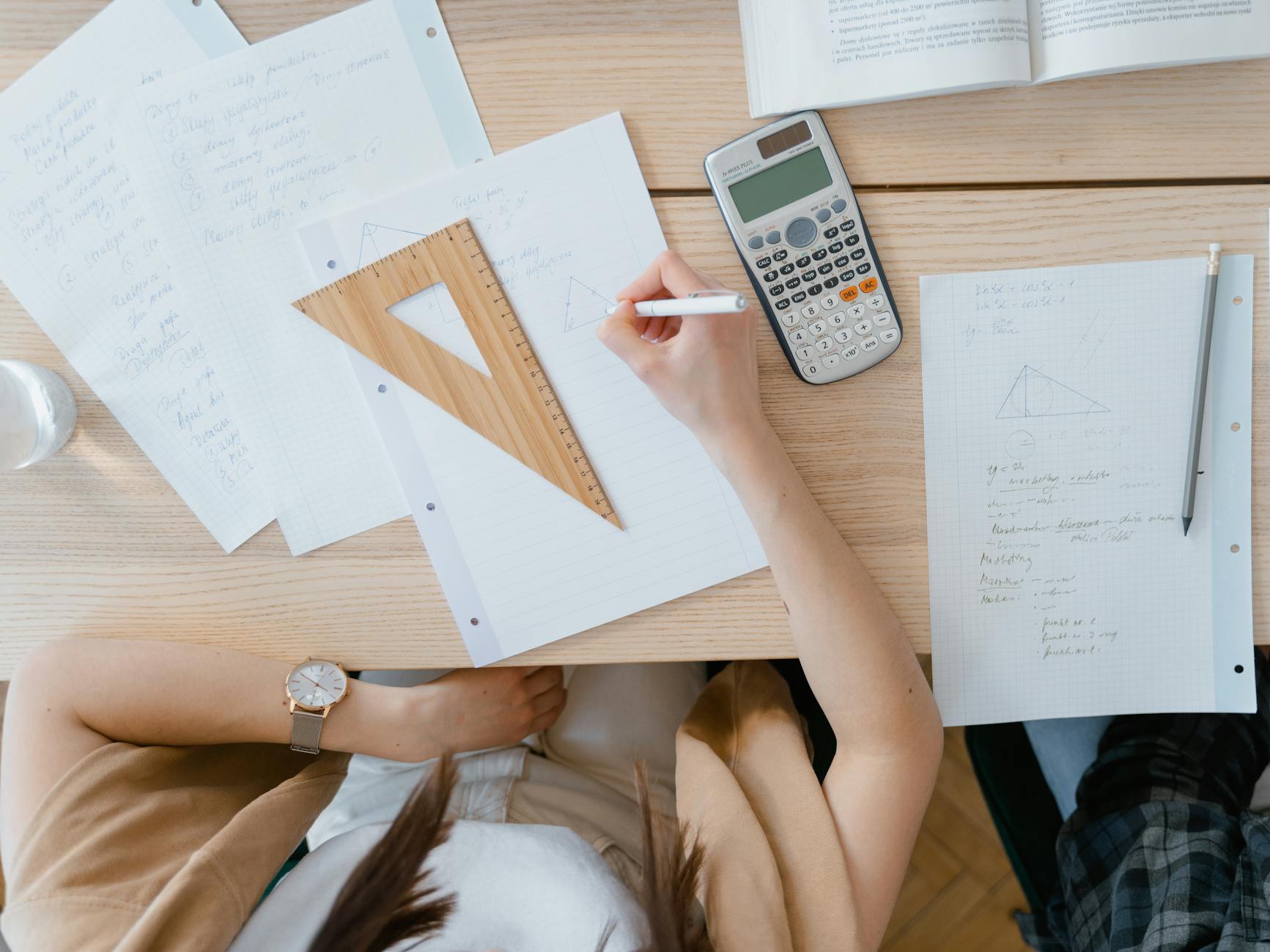 Uczeń w domu liczy zadania z geometrii na kalkulatorze i w zeszycie