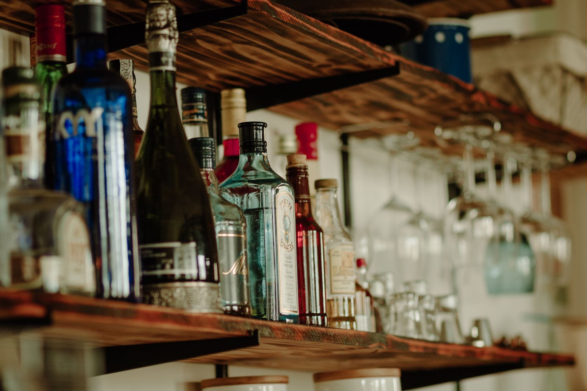 Butelki alkoholu ustawione na rustykalnej drewnianej półce barowej