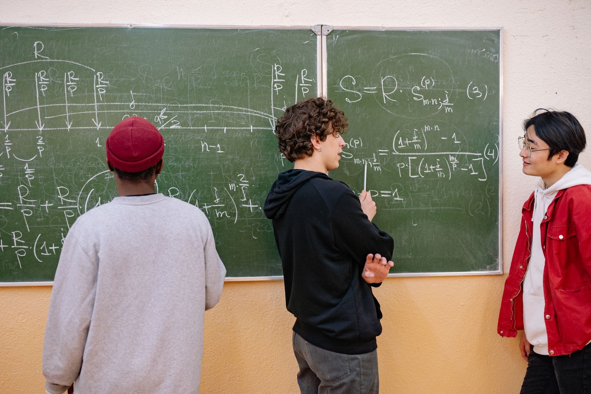 Trójka uczniów przy tablicy omawia zadania maturalne z matematyki
