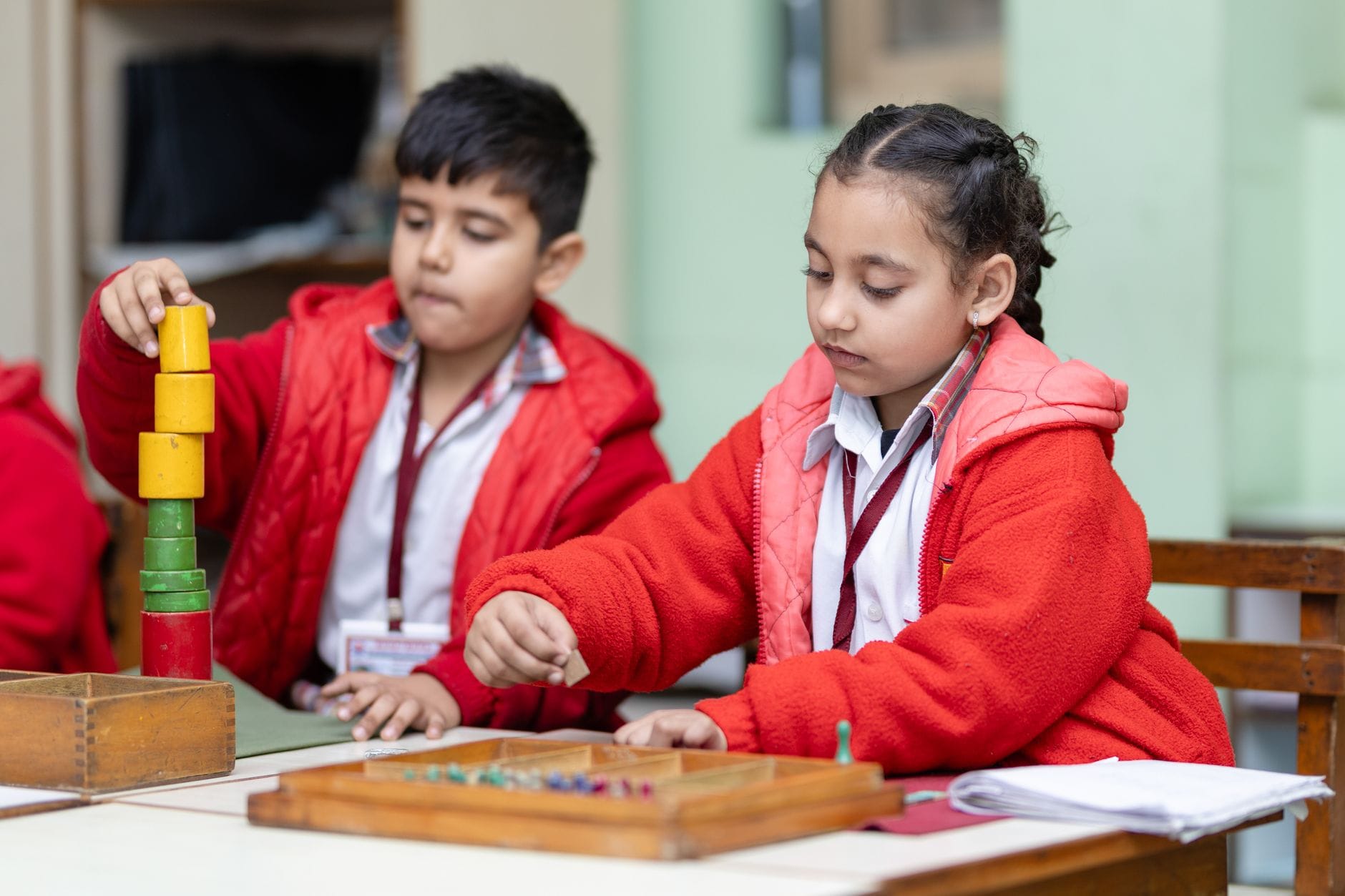 Dwoje dzieci przy stoliku w klasie rozwiązuje zadania edukacyjne