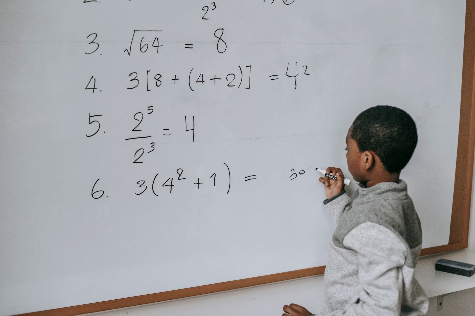 Uczeń przy tablicy rozwiązuje zadanie matematyczne w klasie
