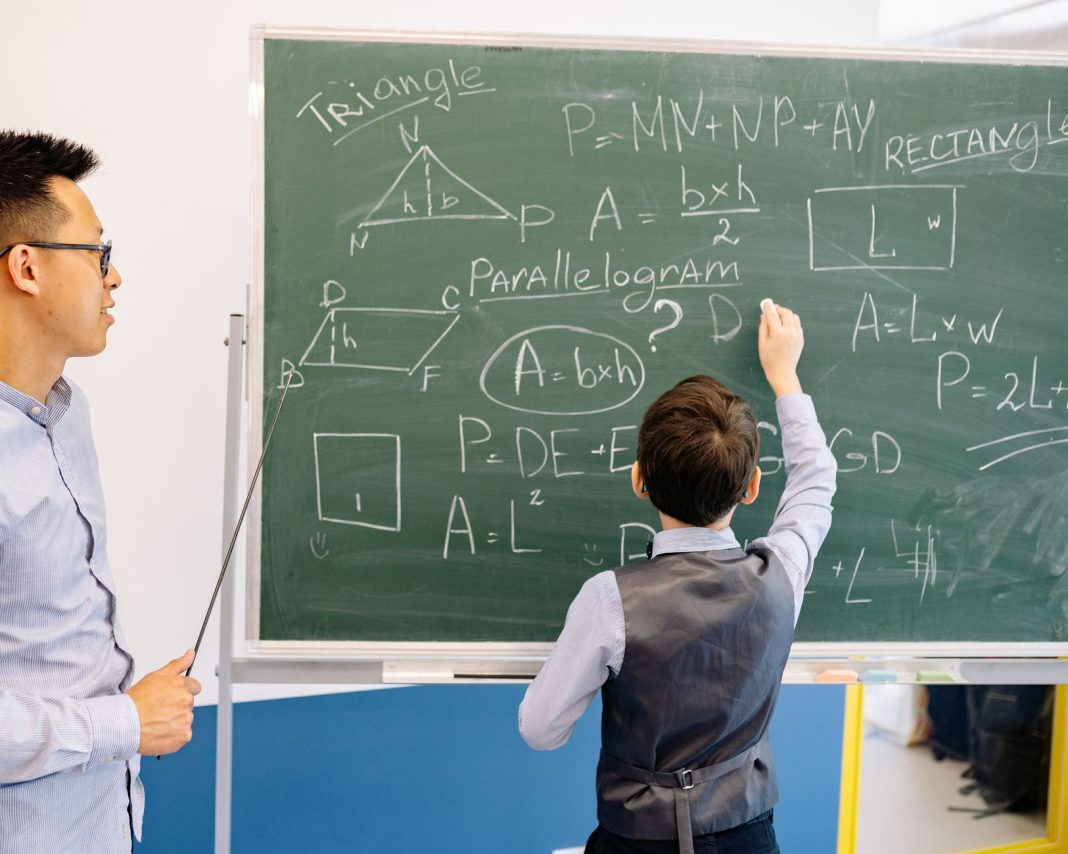 Nauczyciel i uczeń rozwiązują zadania geometryczne przy tablicy Nauczyciel i uczeń rozwiązują zadania geometryczne przy tablicy